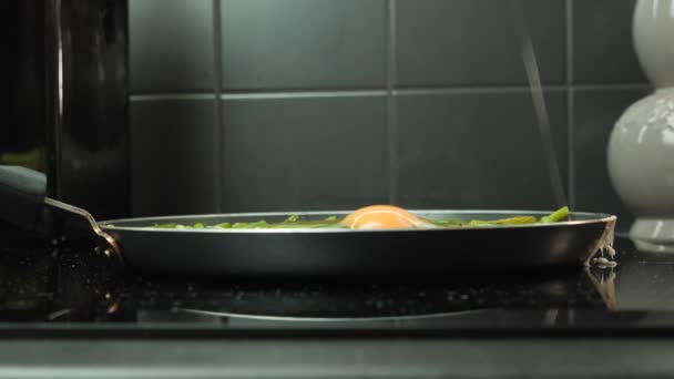 Bryta ägg i kastrull. Människans hand bryter ägg i stekpanna med gröna bönor — Stockvideo