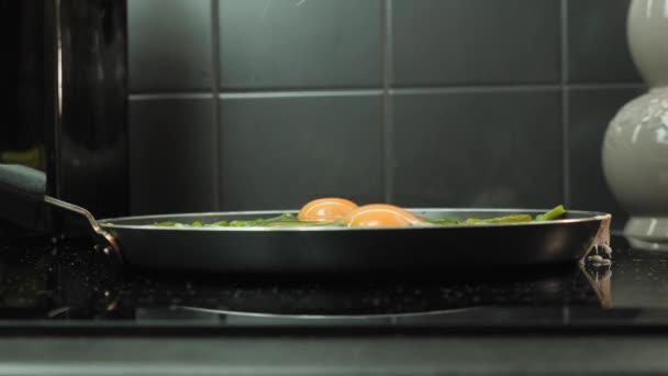 Ręka rozbijająca jajka na patelni. Gotowanie jajecznicy z zielonej fasoli na patelni — Wideo stockowe