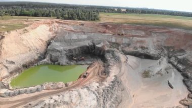 Huge open quarry with mounds of minerals. Machinery working at clay quarry. Open mining