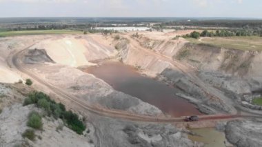 Heavy machinery working at sand quarry. Open pit mining. Iron ore quarry with big lake