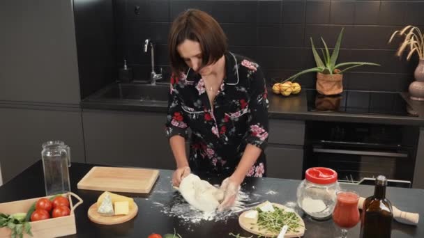Жінка замішує тісто на столі. Виготовлення домашнього хліба або піци. Процес приготування — стокове відео