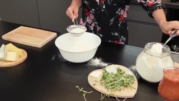 Hembra tamizar la harina por tamiz en un tazón. Mujer preparando deliciosa masa de pizza — Vídeo de stock