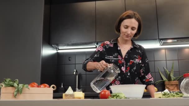 Kvinna matlagning deg hemma kök. Honan tillsätter vatten till mjöl, förbereder degen — Stockvideo