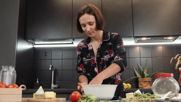 Portrait of young cheerful woman cooking dinner for family in domestic kitchen — Stock Video