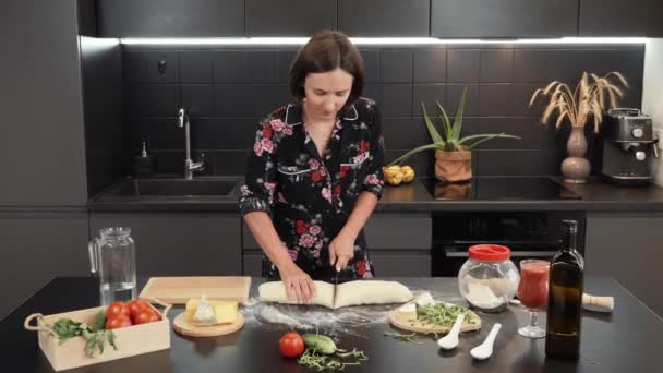 Жінка розрізає тісто на частини ножем. Жіночі руки нарізають сире тісто на шматки — стокове відео