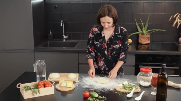 Kadın evde pizza hazırlıyor, geleneksel tarifi kullanıyor, hamuru ahşap masada yoğuruyor. — Stok video