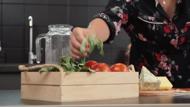 Adicionando manjericão fresco à base de pizza. Mãos femininas adicionando folhas de manjericão à cobertura de pizza — Vídeo de Stock