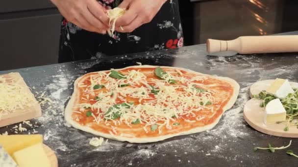 Chef hembra añadiendo queso a base de pizza, preparando margherita de pizza italiana — Vídeos de Stock