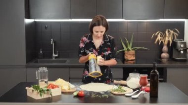 Kadın pizza tabanı için peynir rendeliyor. Evde kadın yemekleri var. Pişirme kavramı