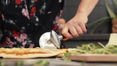 Kesici bıçakla pizza kesmek. Kesiciyle pizza dilimleyen kadın.