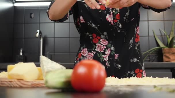 Queijo mozzarella ralado caindo na base de pizza. Mãos femininas polvilhando queijo na pizza — Vídeo de Stock