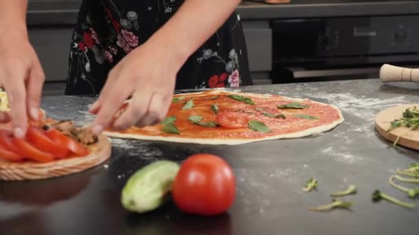 Pizza koken. Vrouwelijke chef-kok die Italiaanse pizza maakt. Vrouw die gesneden tomaten op pizzabasis zet. — Stockvideo