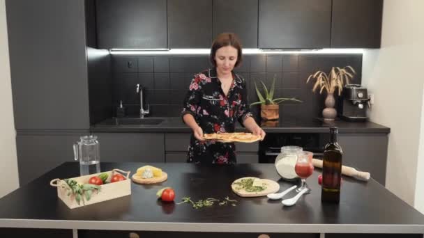 Mujer sonriente alegre pone en la mesa al horno sabrosa pizza. Pizza casera — Vídeos de Stock