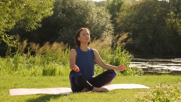Mujer joven haciendo ejercicios de yoga en el parque de verano de la ciudad. Concepto estilo de vida — Vídeos de Stock