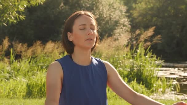 Meditáció napkeltekor. Jóga a parkban reggel. Békés nő meditál a szabadban — Stock videók