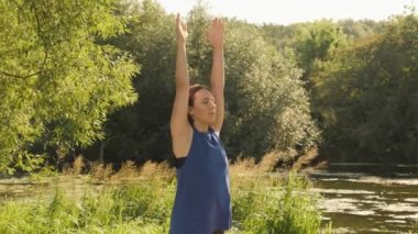 Gün doğumunda parkta meditasyon yapan bir kadın. Sakin kadın sabahları yoga ve esneme egzersizleri yapıyor.
