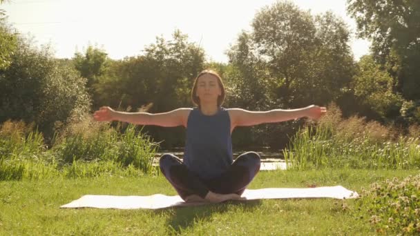 Meditation och yoga koncept. Ung lugn kvinna mediterar i parken på morgonen — Stockvideo