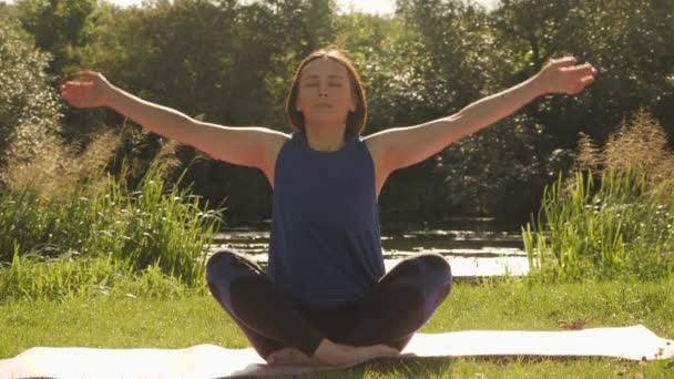 Gyönyörű nő, aki jógázik a nyári parkban napkeltekor. Meditáció reggel — Stock videók