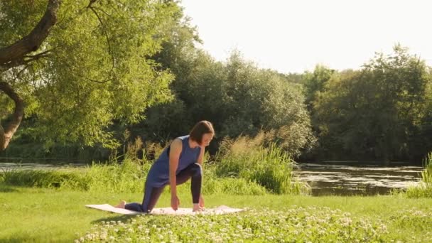 Yoga på morgonen. Kvinna som tränar yoga och stretchar i parken vid soluppgången — Stockvideo