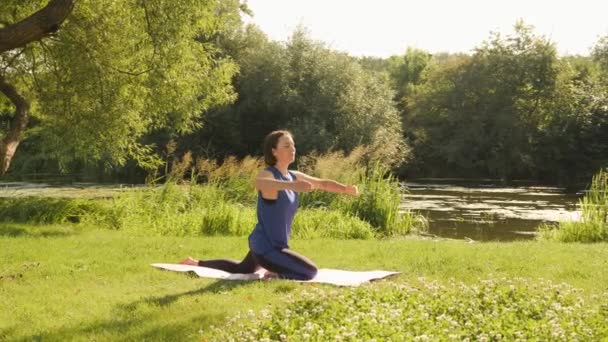 Kadın meditasyon yapıyor ve sabah güneşinin tadını çıkarıyor. Kadın gün doğumunda parkta yoga yapıyor. — Stok video