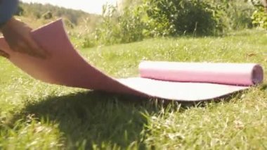 Yoga minderini hazırlamak ve yoga eğitimine hazırlanmak. Kadın egzersiz paspası seriyor