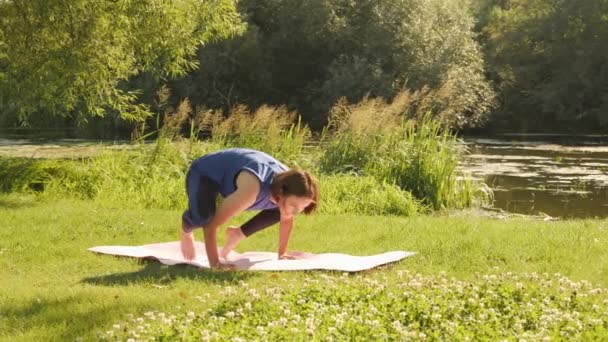 La mujer suspendió la pose de yoga. Mujeres practicando asanas de yoga en el parque por la mañana — Vídeo de stock