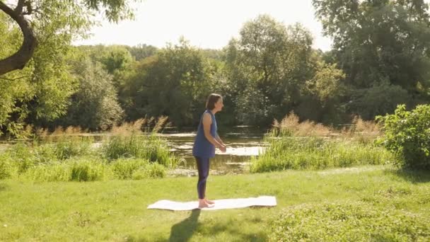 Nowy normalny sport na świeżym powietrzu. Młoda sportowa kobieta rozciągająca swoje ciało w parku o wschodzie słońca — Wideo stockowe