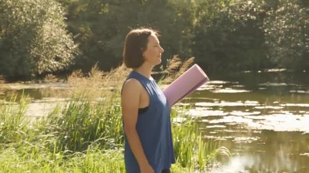 Kvinna med träningsmatta promenader i sommarparken. Kvinna på yogaklass utomhus — Stockvideo