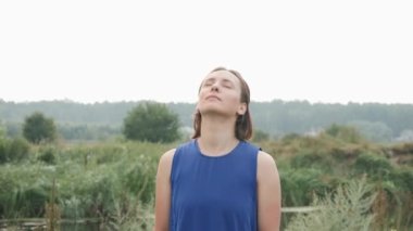 Spor kıyafetleri içinde güçlü atletik bir kadın boynu yoğuruyor, kafa eğme egzersizleri yapıyor.