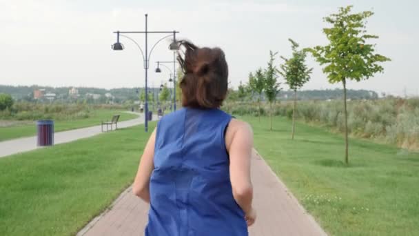 Kvinnan joggar i parken på morgonen. Atletisk kvinna som springer på flodpromenaden — Stockvideo