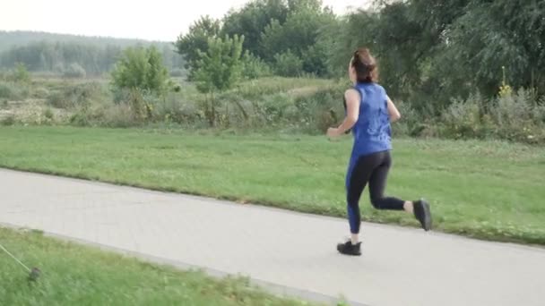 Correr y correr en el parque de la ciudad de la mañana. Mujer haciendo ejercicio al aire libre. Entrenamiento de resistencia — Vídeo de stock