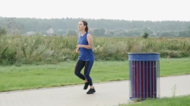 Vrouwelijk joggen in het stadspark in de ochtend. Een vrouw op de vlucht. Gezonde levensstijl — Stockvideo