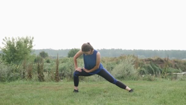 屋外でストレッチ女性。運動を実行する前に公園で女性のストレッチフィット — ストック動画