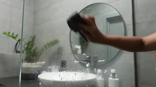 Takarító zuhany. Üveget törölgető nő ronggyal a fürdőszobában. Takarítás a szállodában — Stock videók