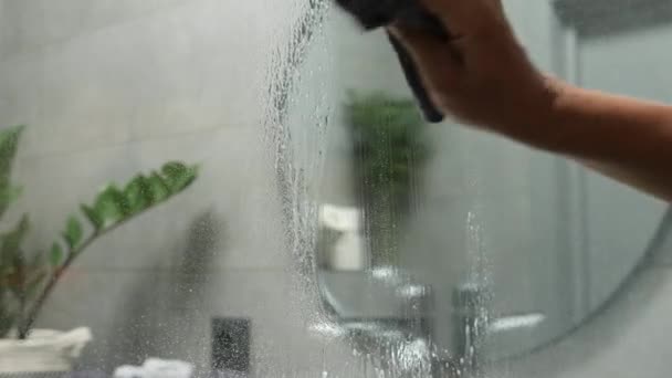 Woman washing shower door with spray and cloth. Female cleaning glass door at bathroom — Stock Video