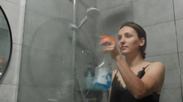 Mujer limpiando la puerta de cristal de la ducha con trapo. Bañera sucia de limpieza y lavado femenino — Vídeos de Stock