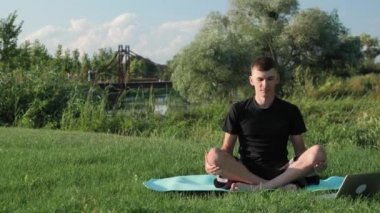 Nilüfer pozisyonunda yoga minderinde oturan ve elini kaldıran adam. Sabah meditasyonu