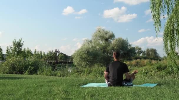 Meditating outdoors. Man sitting in pose of lotus, looking at sunrise and meditating — Stock Video
