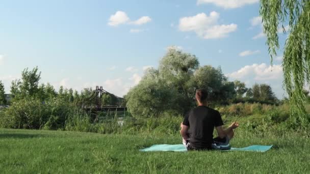 Meditando al aire libre. Hombre sentado en pose de loto, mirando al amanecer y meditando — Vídeos de Stock