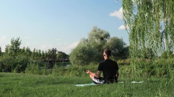 Conceito de ioga e meditação. Meditação matinal no parque. Homem praticando ioga — Vídeo de Stock
