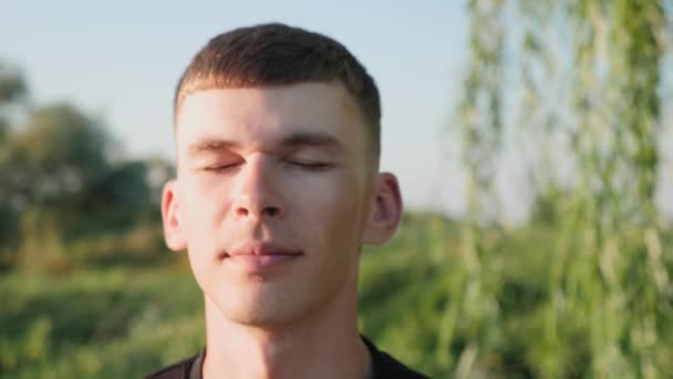 Cara masculina com os olhos fechados, de perto. Meditação de homem no parque de manhã. Yoga praticando — Vídeo de Stock