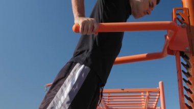 Dışarıdaki düzensiz parmaklıklar üzerinde egzersiz yapan bir adam. Spor barlarında şınav çeken erkek sporcu