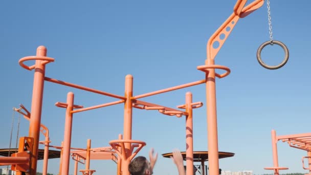 Hombre fuerte ejercitándose en barras irregulares. Hombre atlético haciendo pull-ups en la barra horizontal al aire libre — Vídeo de stock