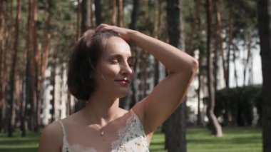 Şehir parkında genç bir kadın. Güzel, neşeli kadın gün batımında parkta duruyor.