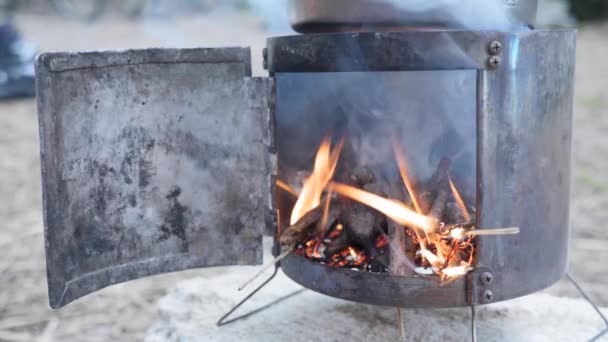 Yemek pişirmek için odun sobası. El, seyyar yemek fırınına tahta çubuklar koyuyor. — Stok video