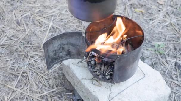 L'uomo mette pentola d'acqua sul fuoco per cucinare sulla natura. Pentola su stufa a legna — Video Stock