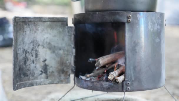 Putting firewood into stove on nature. Hand puts wood sticks to burning stove — Stock Video