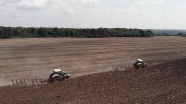 Harrow sistemli traktörler tarlayı sürüyor ve tarım tarlasında çalışıyor.