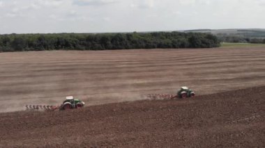 Traktörler tozlu çorak toprağı sürüyorlar. Tarım makineleri tarım alanında çalışıyor.