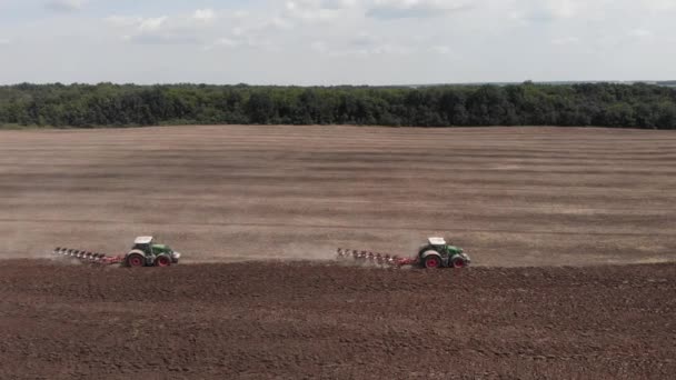 Tractores cultivando en el campo de la granja, pateando tierra polvorienta en el aire. Agroindustria y cosecha — Vídeos de Stock